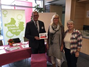 Foto: Verbandsbürgermeister Lothar Röser, Gleichstellungsbeauftragte Susanne Christ und Doris Eyl-Müller vor ihrem Stand. 