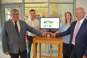 Foto: Landrat Achim Hallerbach (rechts) gab gemeinsam mit dem zuständigen Dezernenten Michael Mahlert (links), Lisa Schubert und Markus Fries von der Stabsstelle Digitalisierung durch Drücken des roten Knopfes den Startschuss für die beiden access points im Kreishaus. Damit bietet der Landkreis Neuwied als einer der ersten Landkreise eine attraktivere Ausgestaltung von Wartezonen.